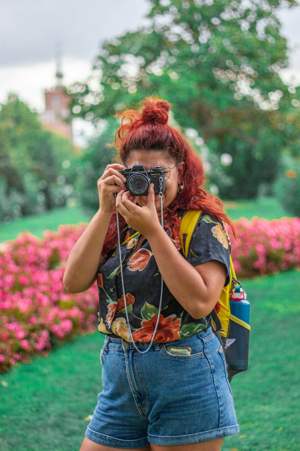 woman taking photo while standing near flowers